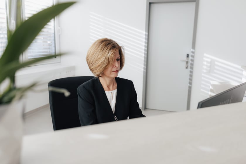 Frau mit blonden Haaren sitzt am Schreibtisch in einem Büro.