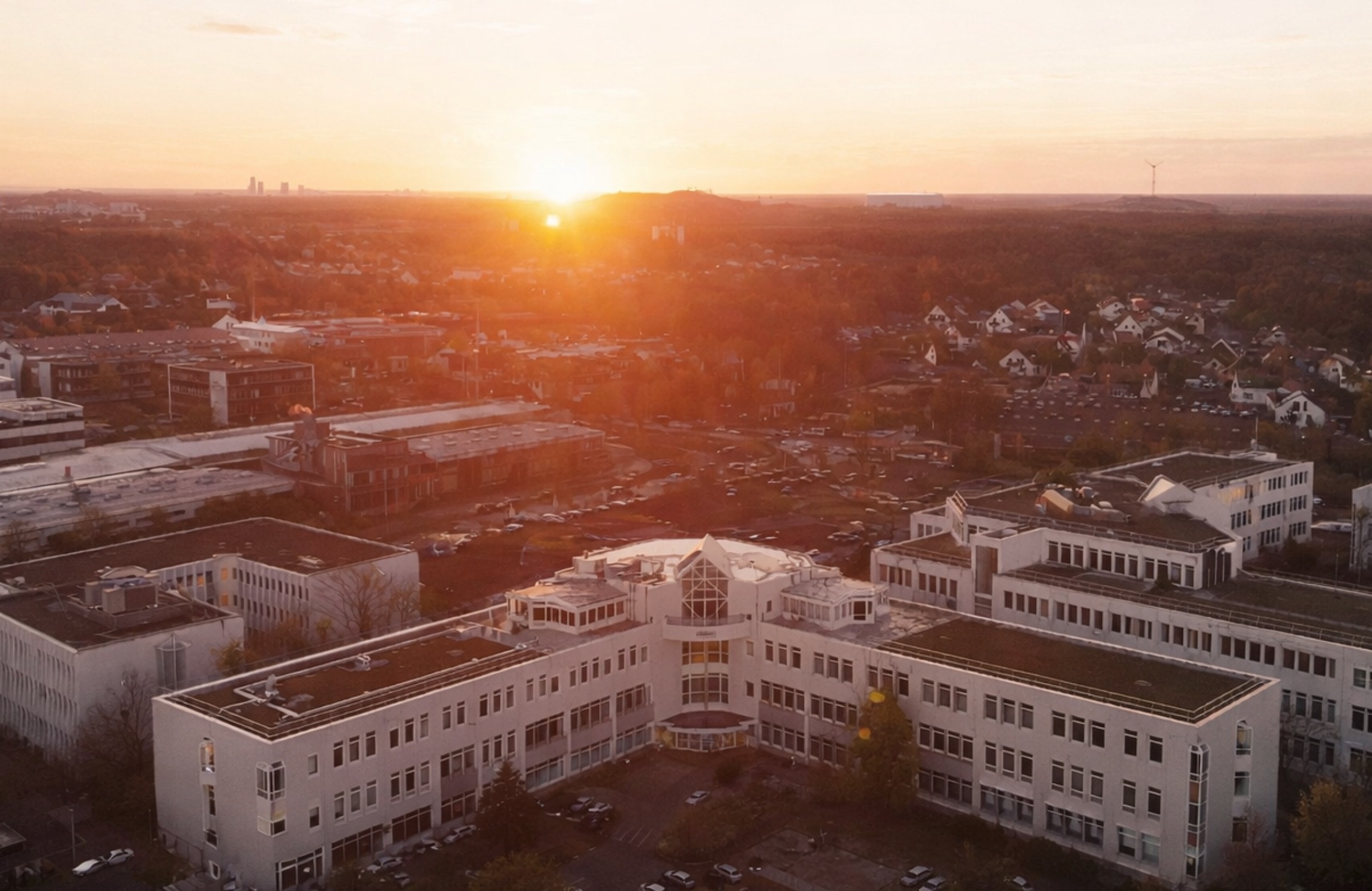 Sonnenuntergang über einer Stadt mit modernen Gebäuden.