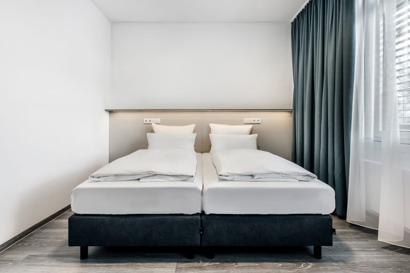 Modernes Hotelzimmer mit zwei Betten und Vorhängen