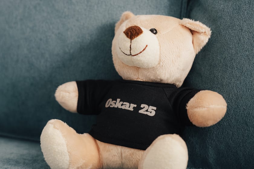 Plüschbär mit schwarzem Shirt auf einem blauen Sofa.