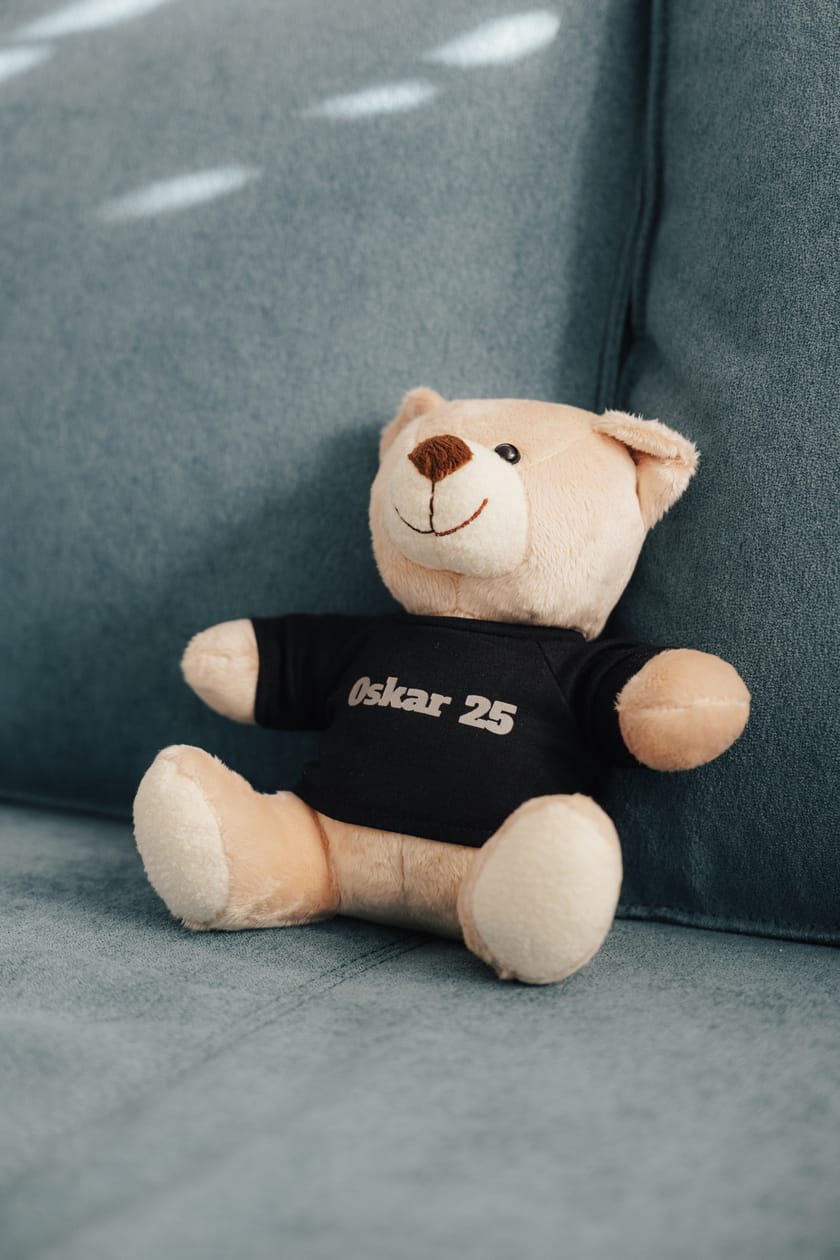 Plüschbär mit schwarzem Shirt auf einem blauen Sofa.