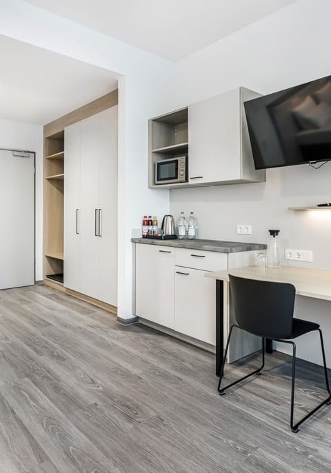 Helles Hotelzimmer mit Tisch, Stühlen und Küchenzeile.