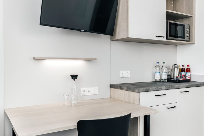 Hotelzimmer mit Küchenzeile, Fernseher und Tisch.