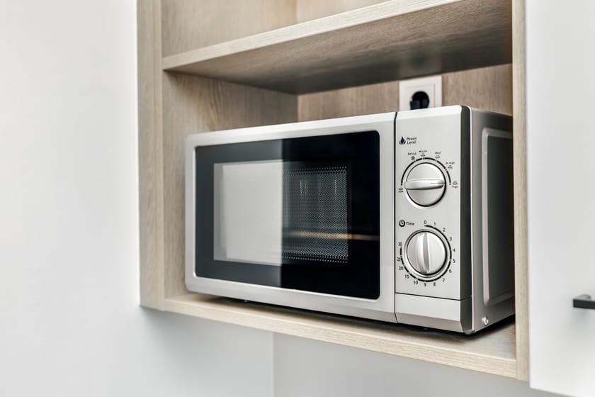 Moderne Mikrowelle auf einem Holzregal im Hotelzimmer.