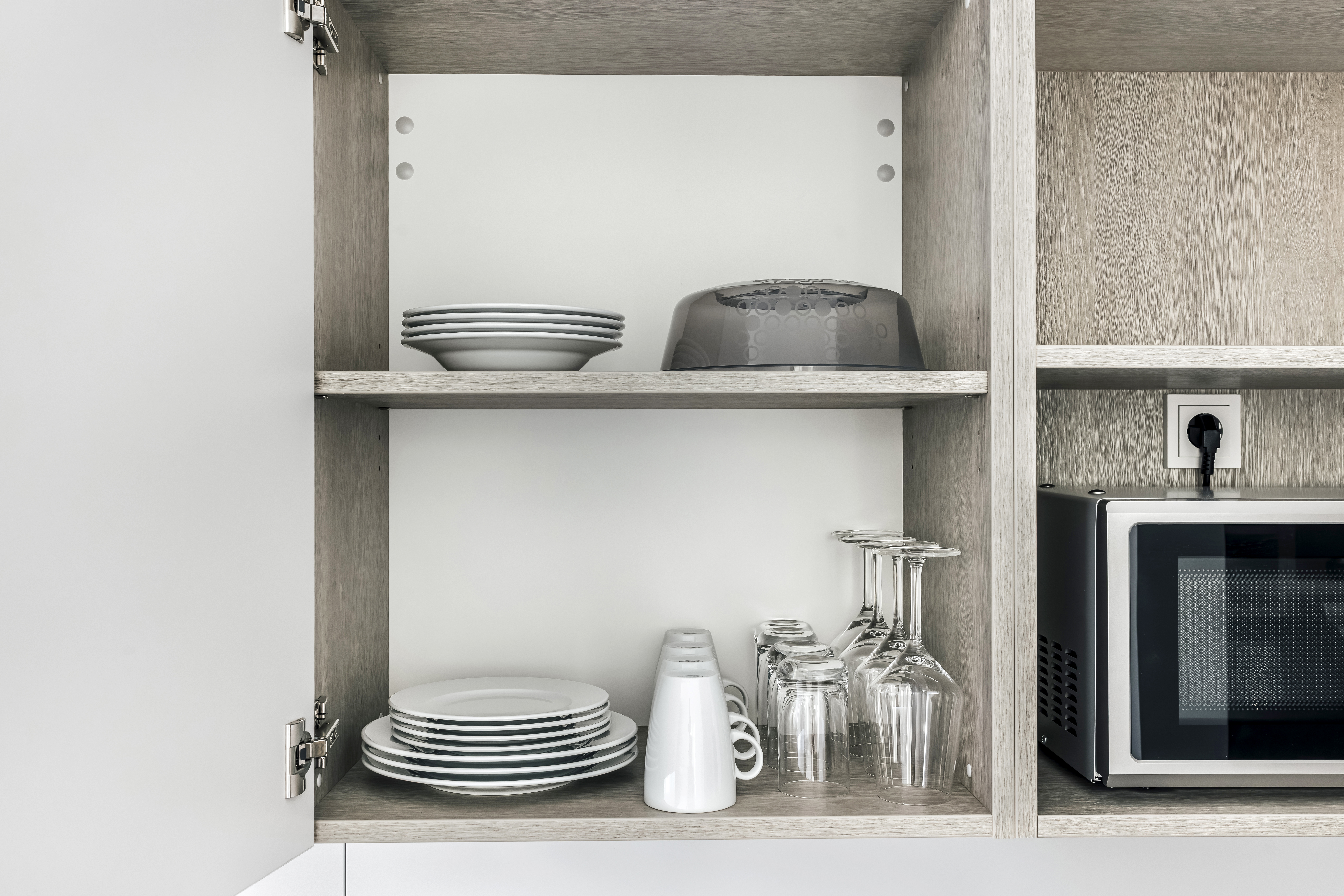 Küchenregal mit Tellern, Gläsern und einer Mikrowelle.