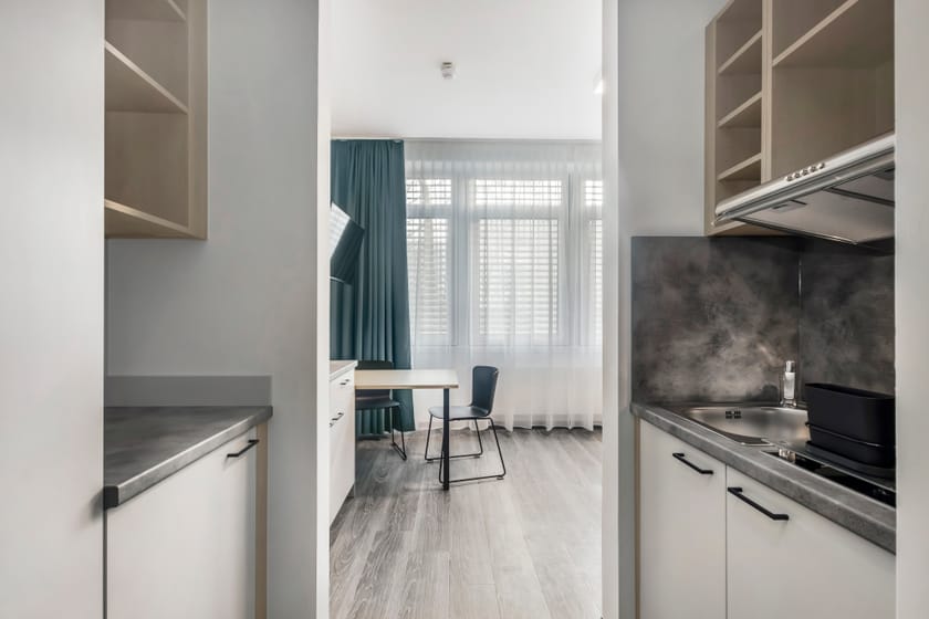 Ein modernes Hotelzimmer mit Küche und Schreibtisch.