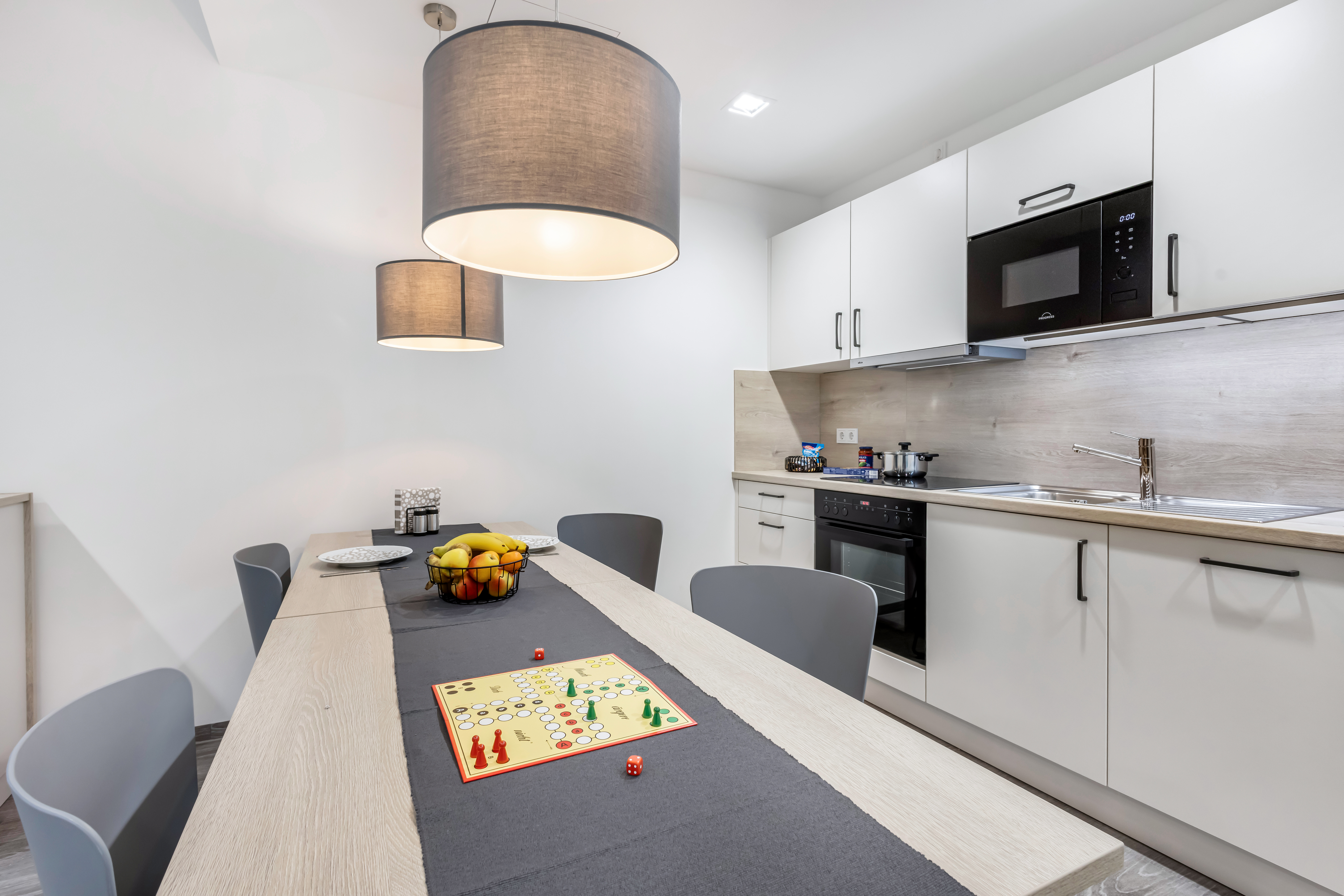 Modernes Hotelzimmer mit Tisch, Stühlen und Küchenzeile.