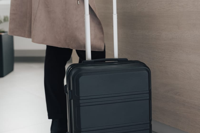 Schwarzer Koffer neben einer Person am Empfangstresen.