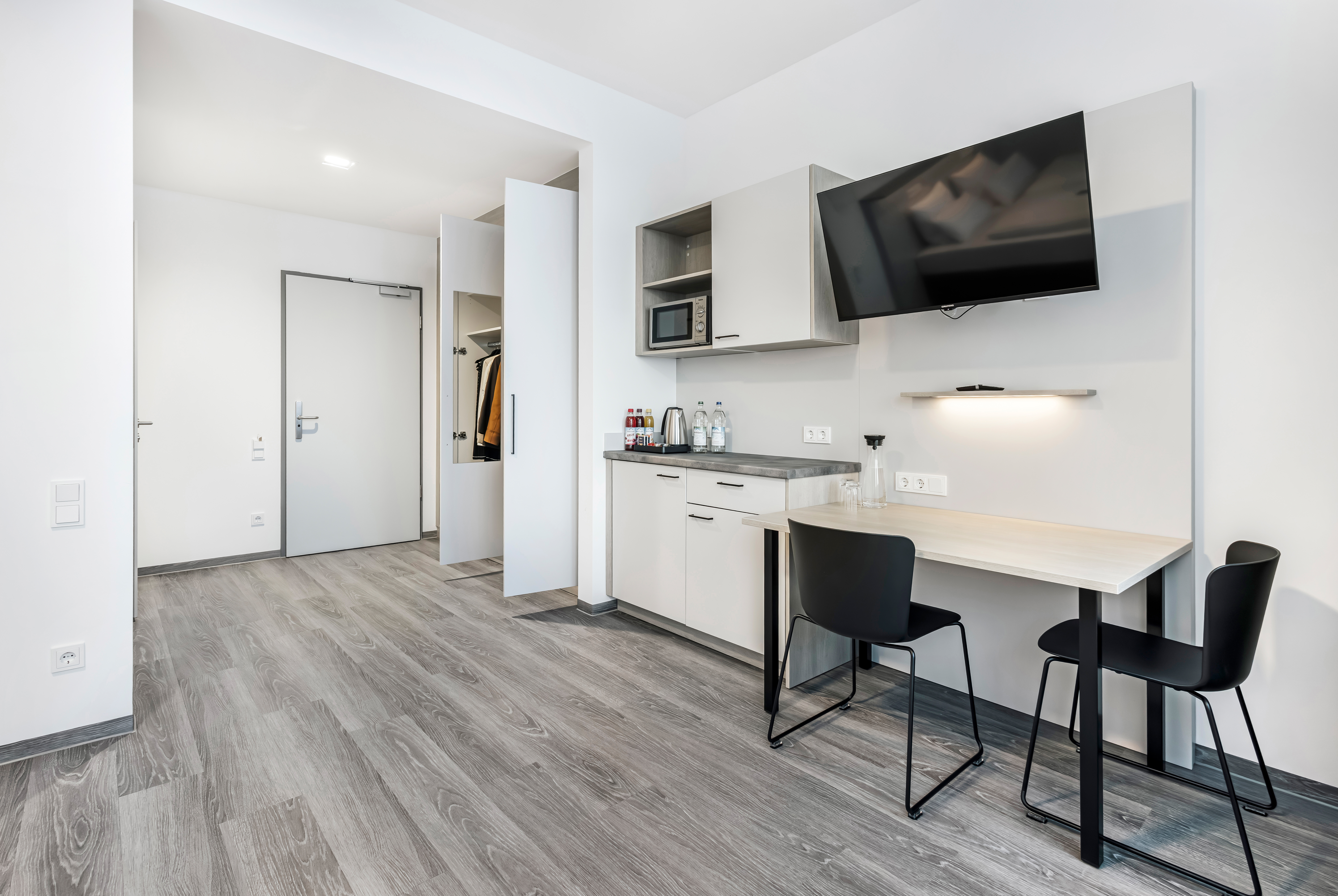 Modernes Hotelzimmer mit Tisch, Stühlen und Fernseher.