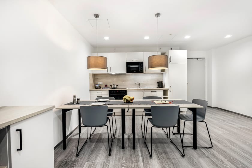 Moderne Hotelzimmerküche mit Tisch und Stühlen.