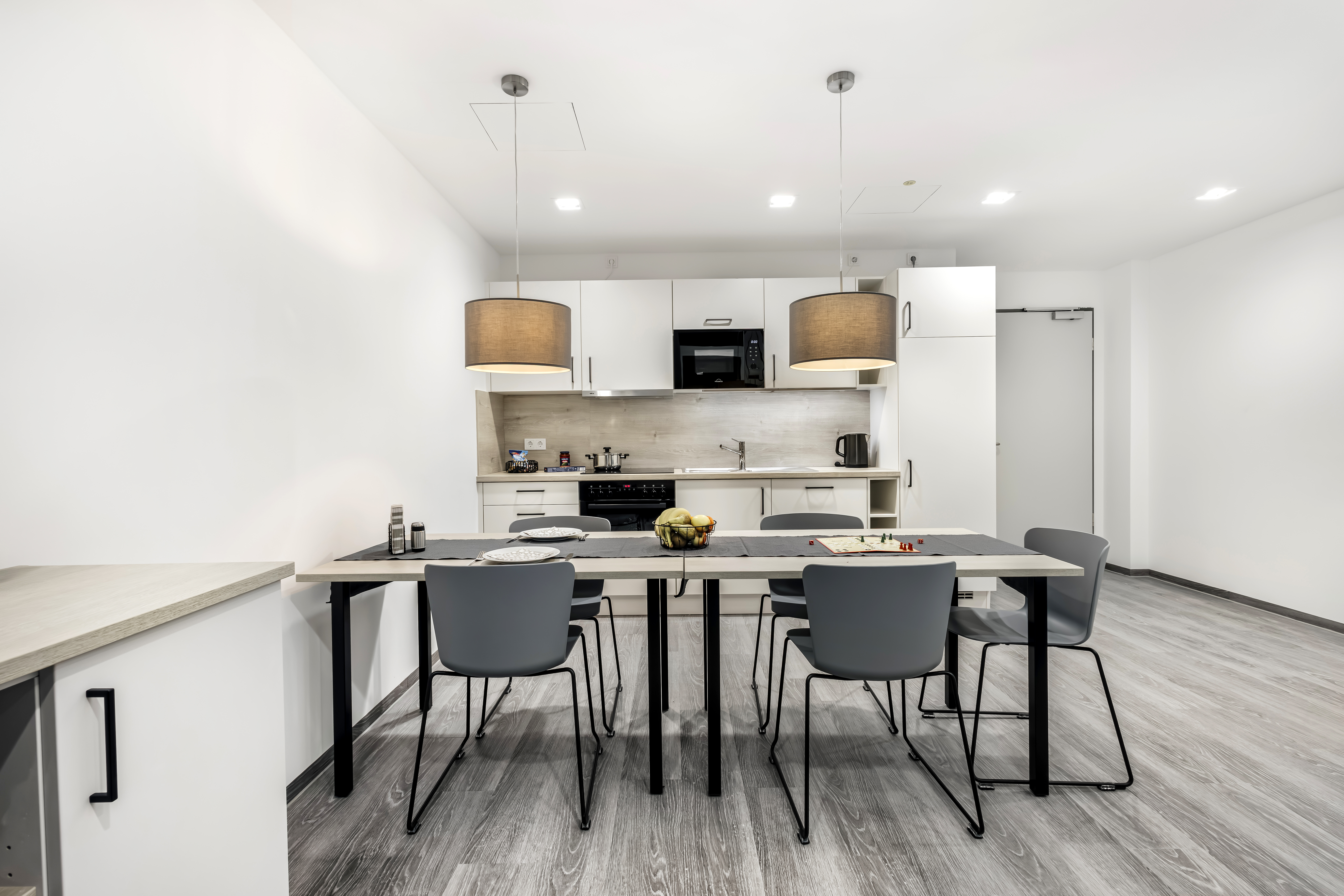 Moderne Hotelzimmerküche mit Tisch und Stühlen.