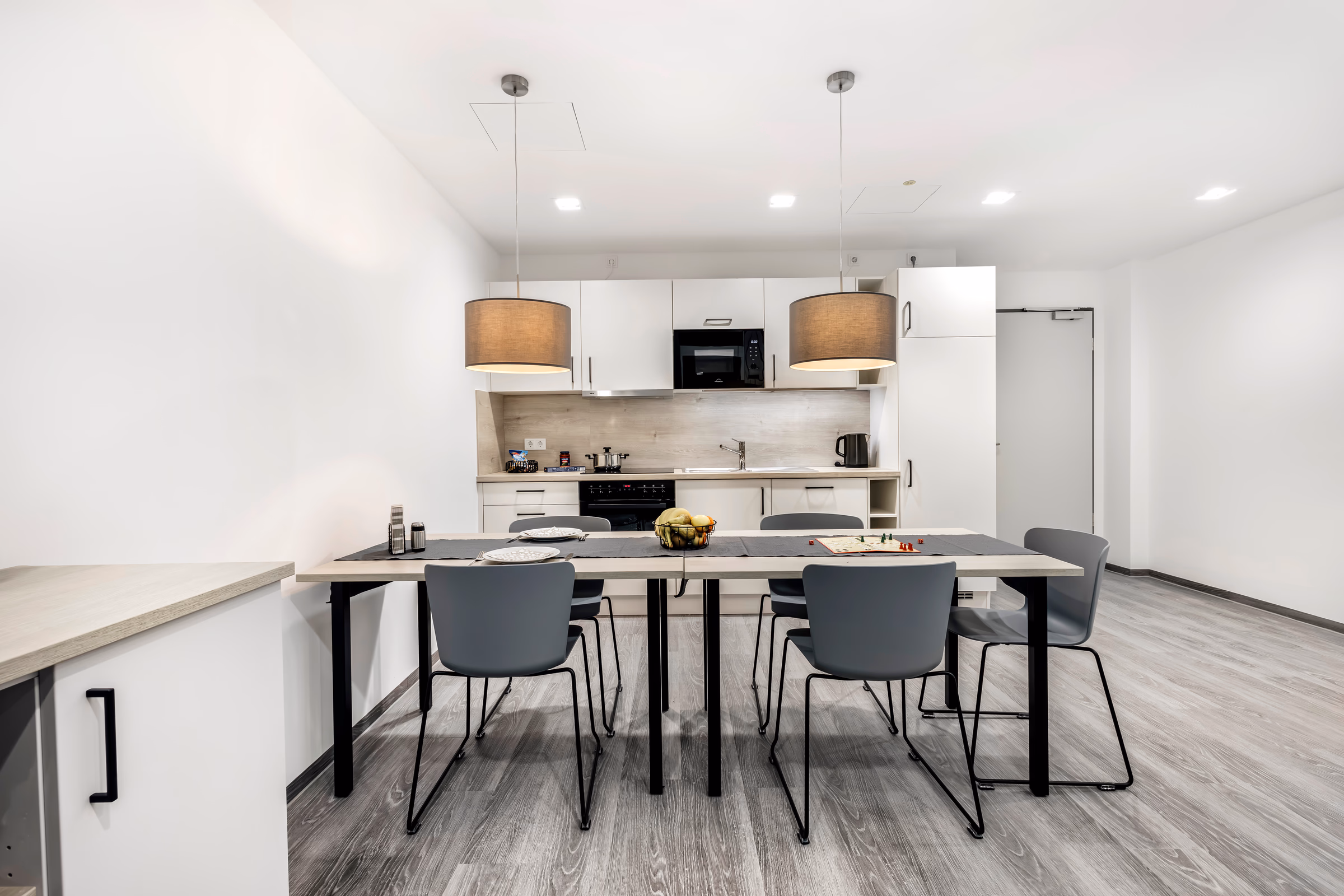 Moderne Hotelzimmerküche mit Tisch und Stühlen.