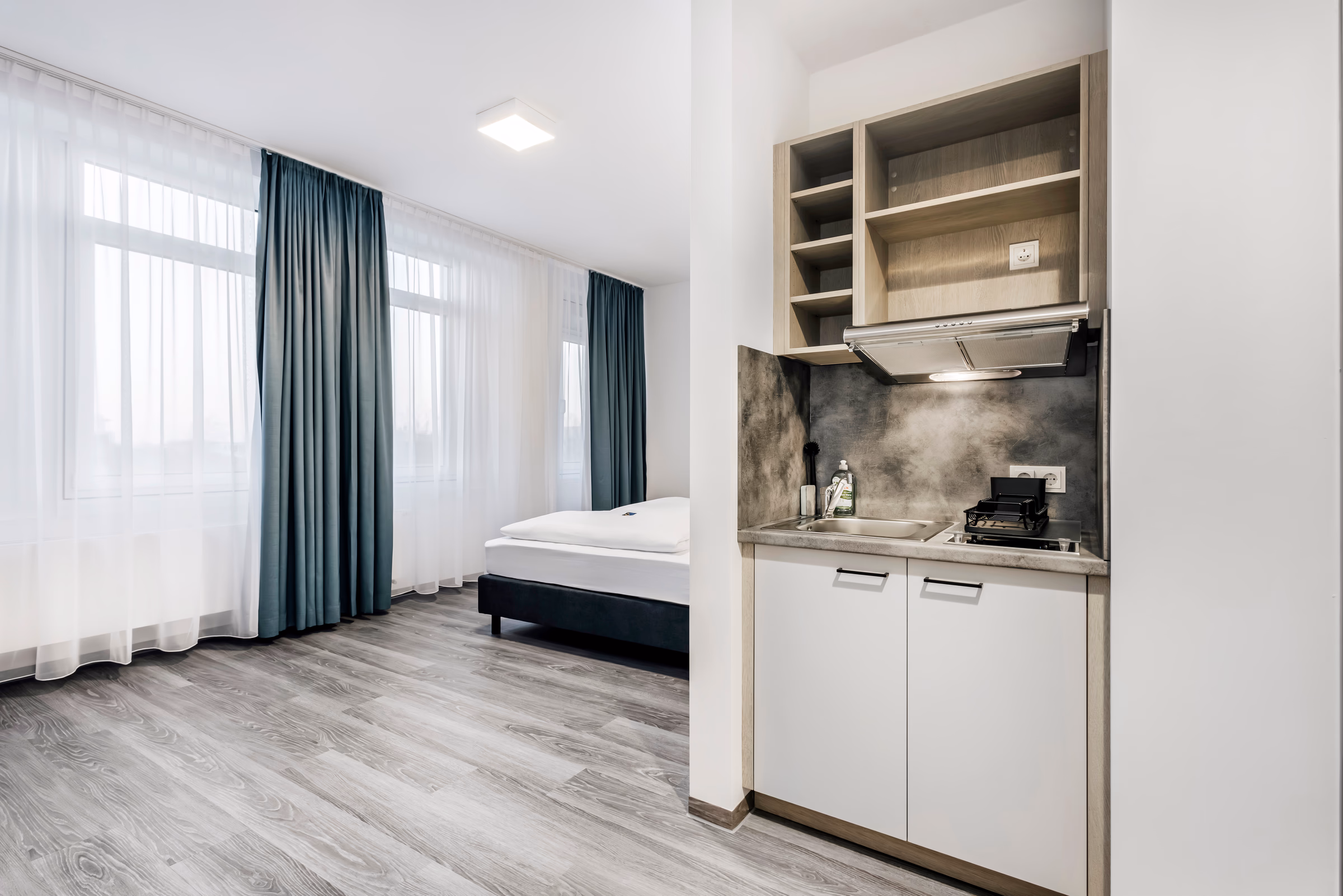 Modernes Hotelzimmer mit Kochnische und Fensterblick.