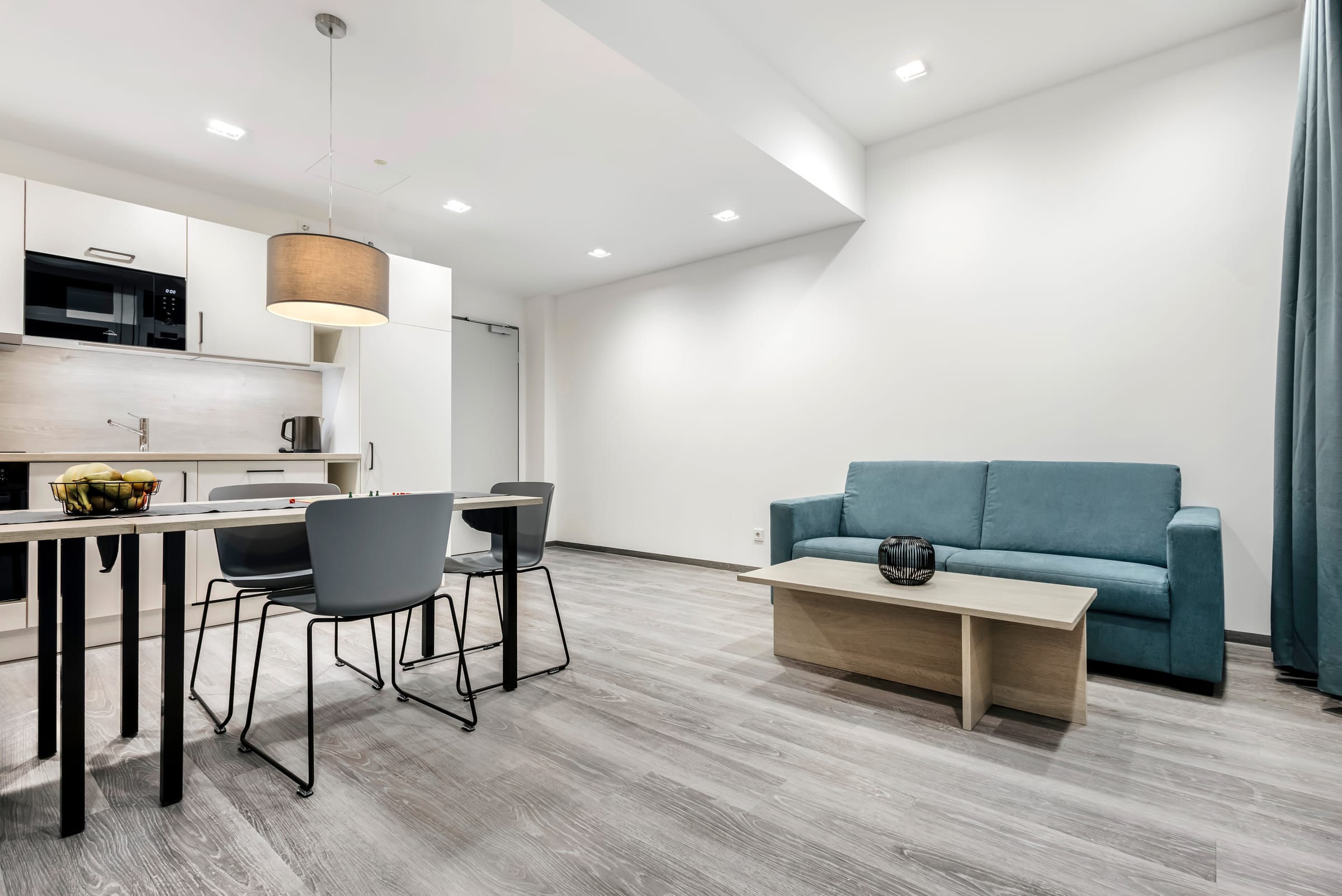 Helles Hotelzimmer mit Küche und Sitzbereich.