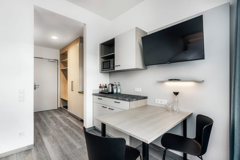 Modernes Hotelzimmer mit Tisch, Fernseher und Kühlschrank.