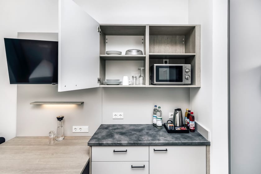 Moderne Küche in einem Hotelzimmer mit Mikrowelle und Geschirr