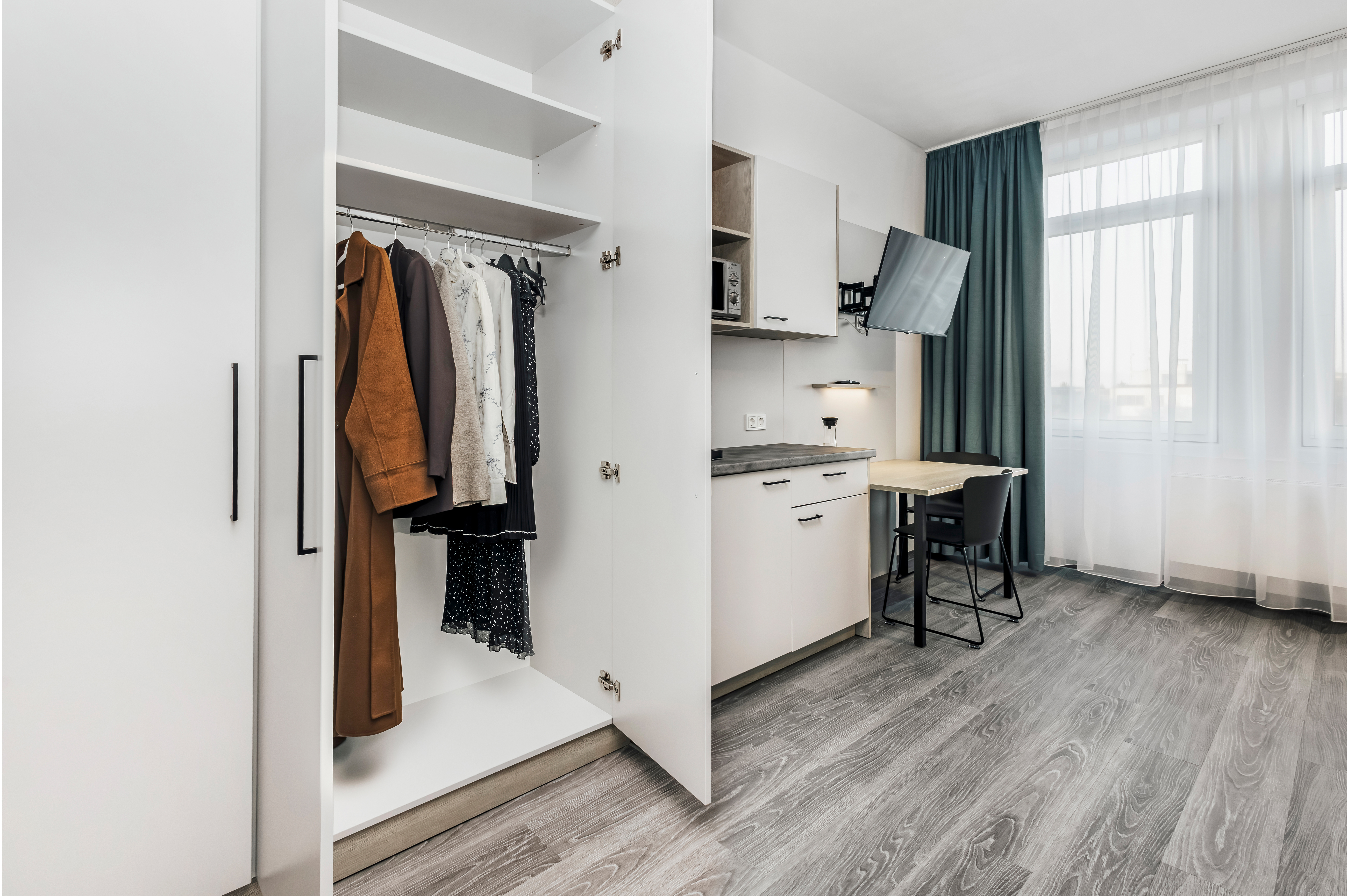 Ein modernes Hotelzimmer mit offenem Schrank und Schreibtisch.