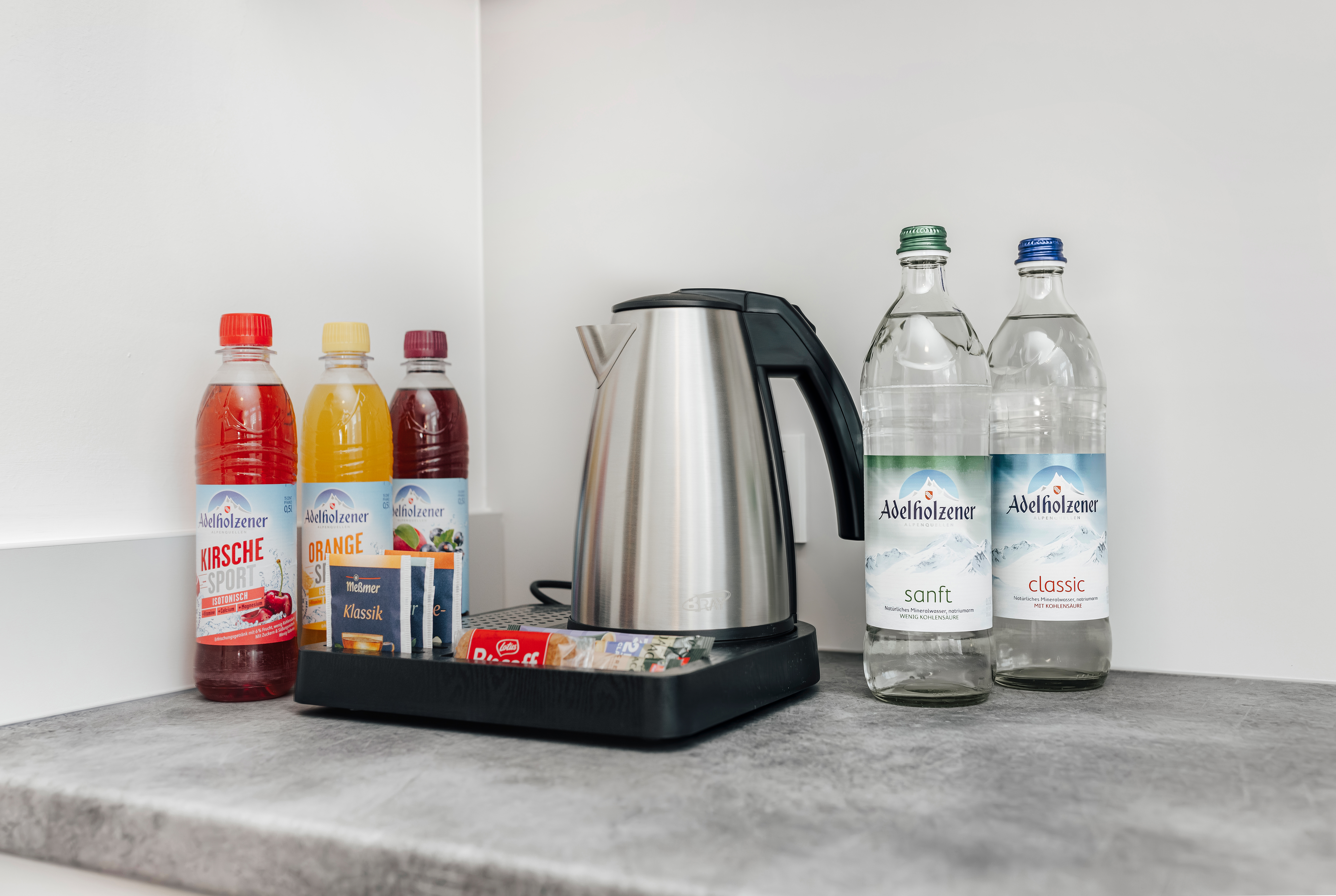 Wasserkocher und verschiedene Getränke in einem Hotelzimmer.