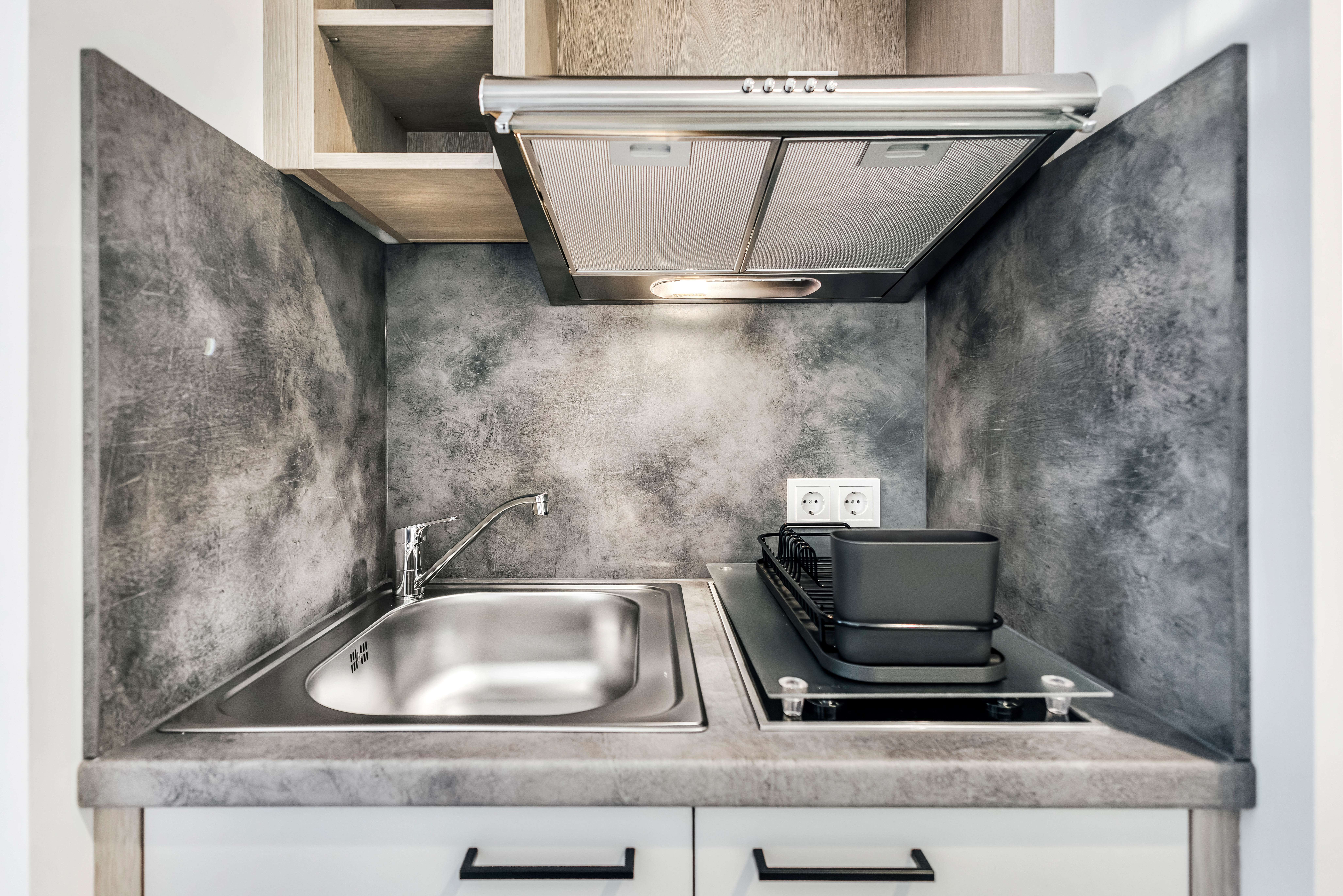 Moderne Küchenzeile mit Spüle und Kochfeld im Hotelzimmer.