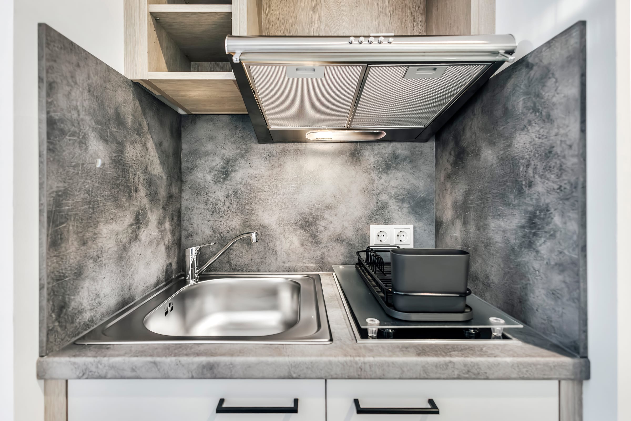 Moderne Küchenzeile mit Spüle und Kochfeld im Hotelzimmer.