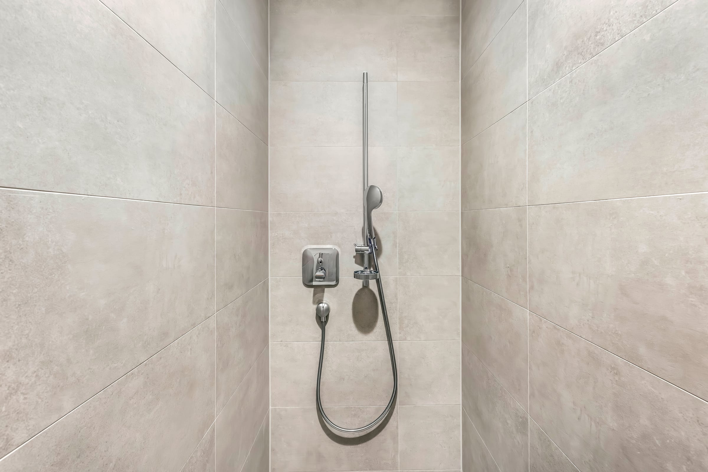 Moderne Dusche mit grauen Fliesen und Handbrause