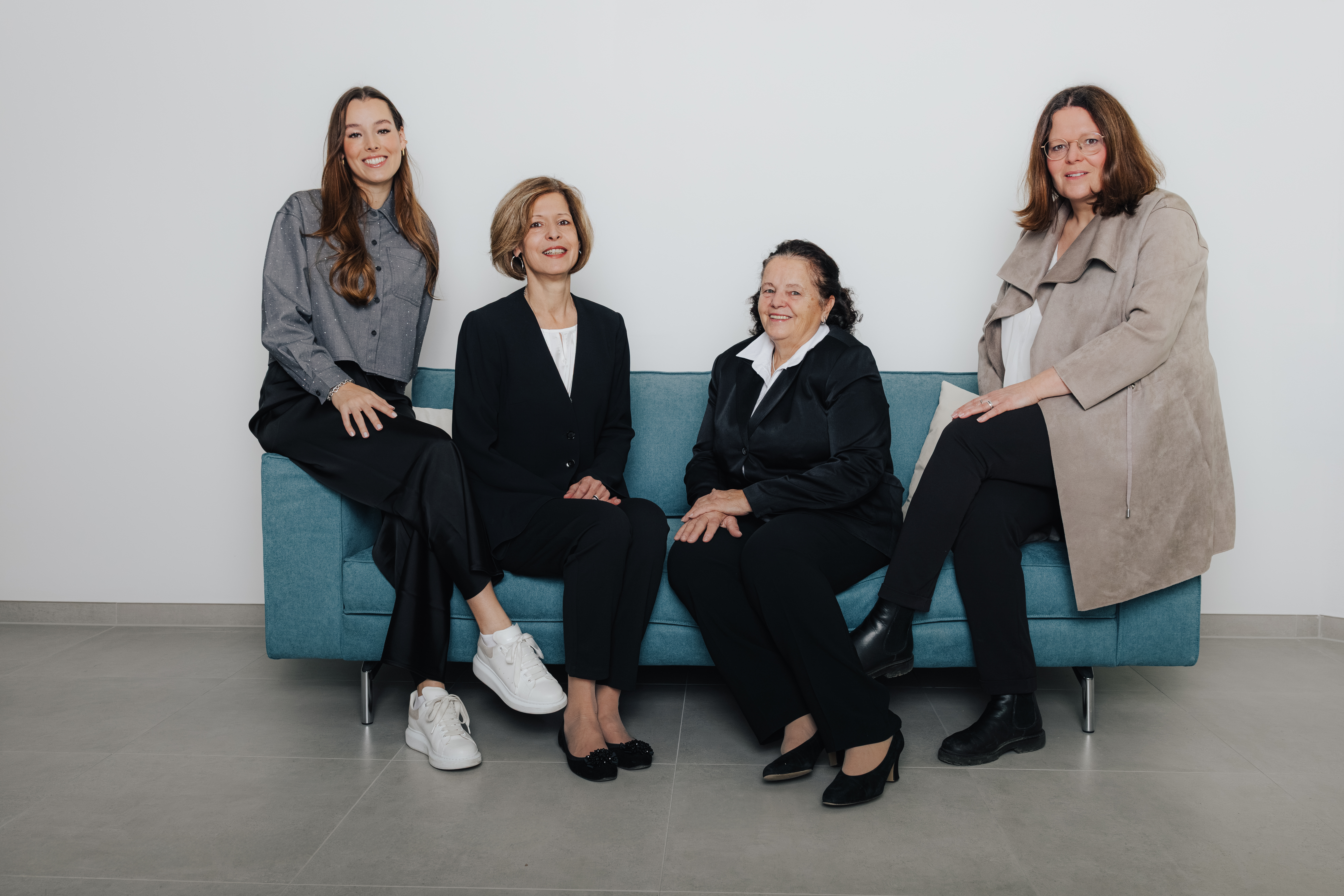 Vier Frauen sitzen auf einem blauen Sofa in einem modernen Raum.