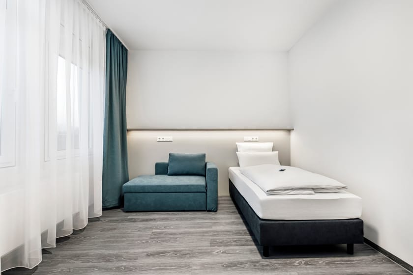 Modernes Hotelzimmer mit einem Einzelbett und einer Sitzecke.