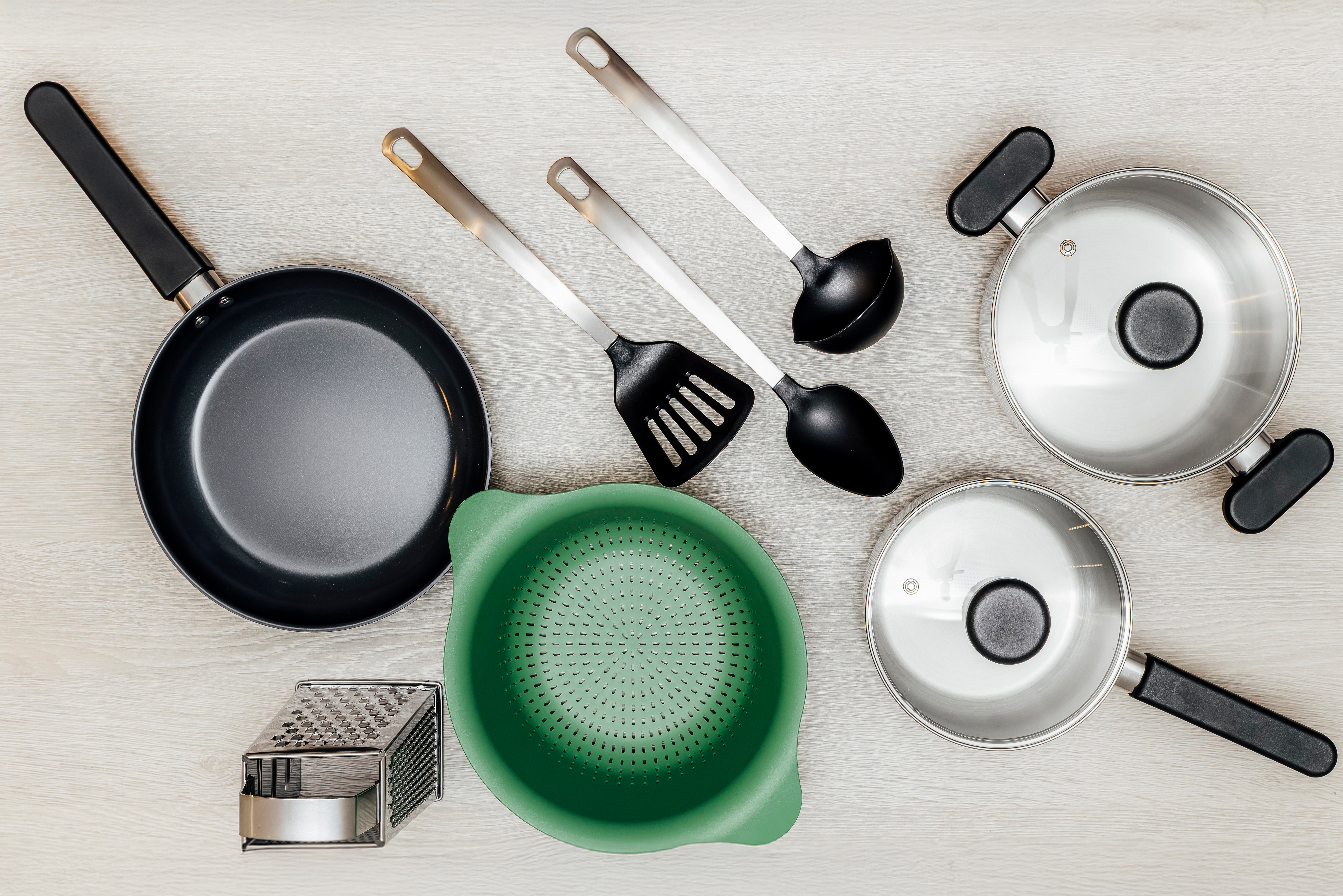 Küchenutensilien wie Töpfe, Pfannen und Küchengeräte auf einem Tisch.