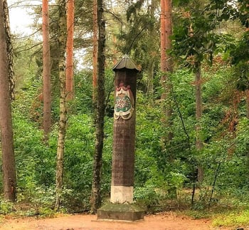 Ein Wachturm aus Stein im Wald, umgeben von Bäumen.